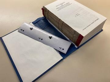a book open with its case detatched showing uncut playing cards as the spine lining.