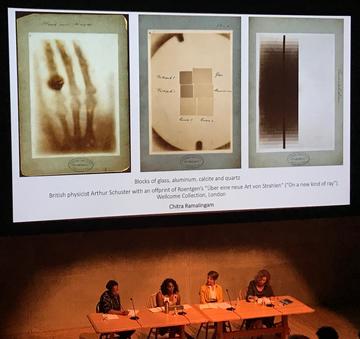 Discussion panelists sitting below projection screen with images of historic photographs