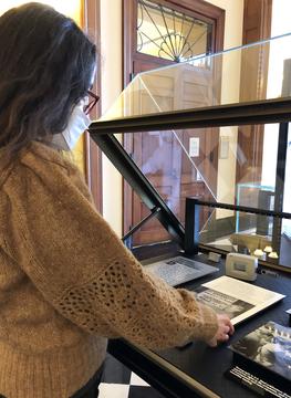 A woman taking a reading from a environmental monitor in an exhibit case.