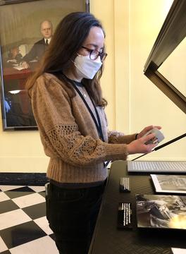 A woman taking a reading from a environmental monitor in an exhibit case.