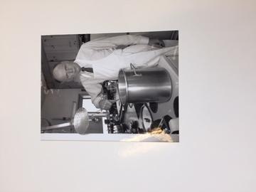 A photograph of a man wearing an apron standing over a tall pot.