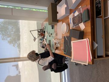 A person working on a book cover at her bench.  