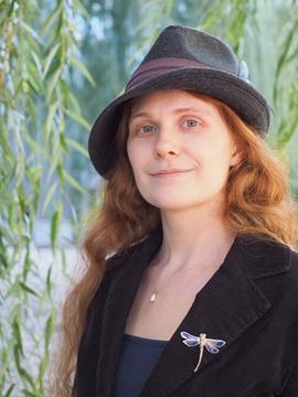 A person with long red hair wearing a hat.