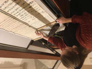 A woman unrolling a scroll in a display case.