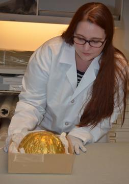 A woman with long hair wearing a lab coat and working with an object.