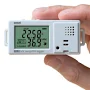 Hands holding a small white box with a screen showing temperature and relative humidity. 