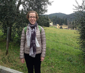 A woman with greenery behind her.