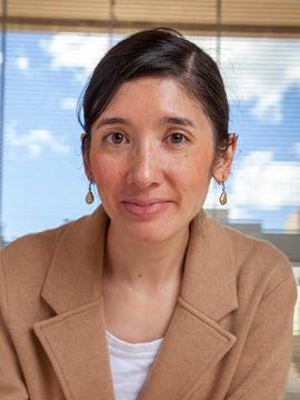 A woman with earrings wearing a blazer.