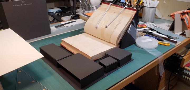 An open book within a support mount with small black boxes all around. 