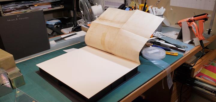 A book with an open foldout with a large piece of matboard underneath/ 