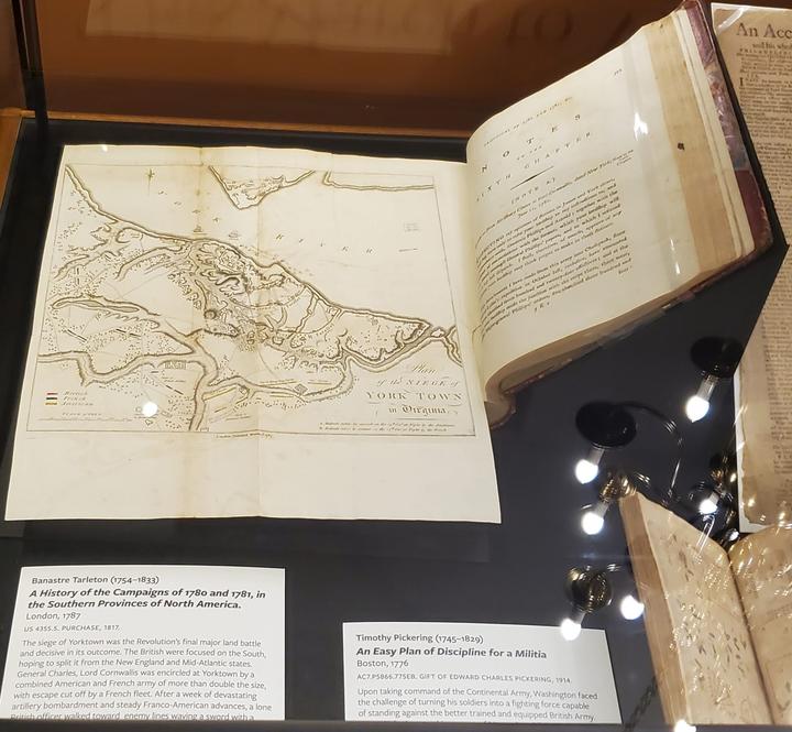 A mounted foldout in a book inside an exhibition case. 