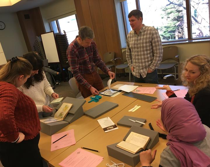 People gathered around a table looking at library materials.