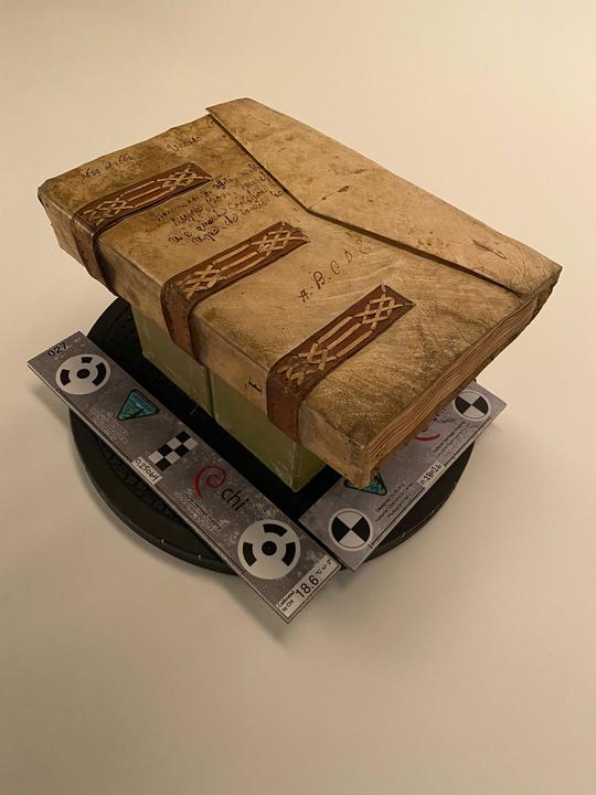 A book bound in parchment on a small platform ready to be photographed. 