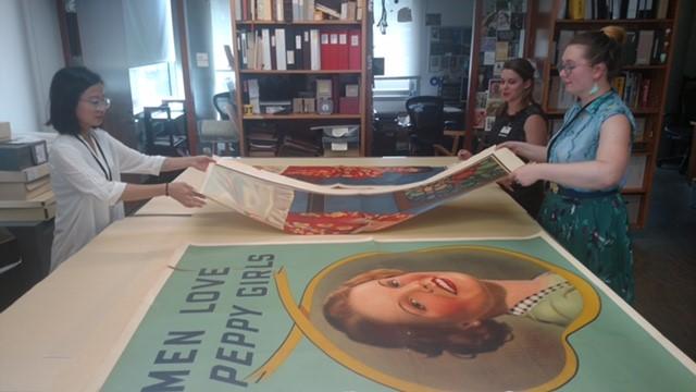 Large, colorful posters spread out on a table.