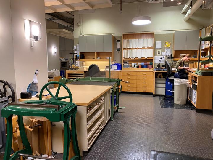 A large open space with workbenches and built-in drawers around the perimeter and cabinets above.