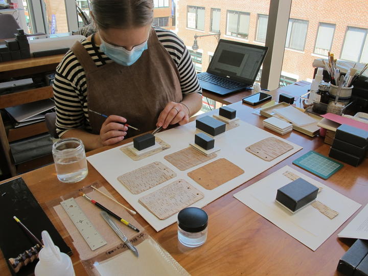 A woman working on repairing loose pages from a book.
