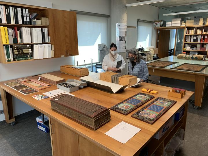 Two people standing behind a table filled with Tibetan and Mongolian materials. 